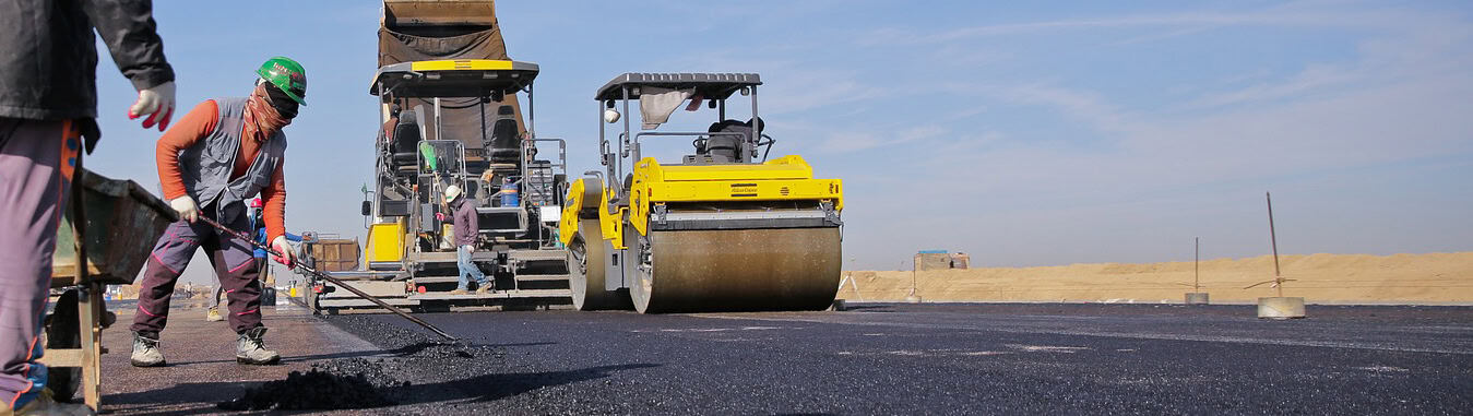 Expert crew performing professional asphalt paving on a commercial roadway using high-grade heavy machinery for a smooth finish.
