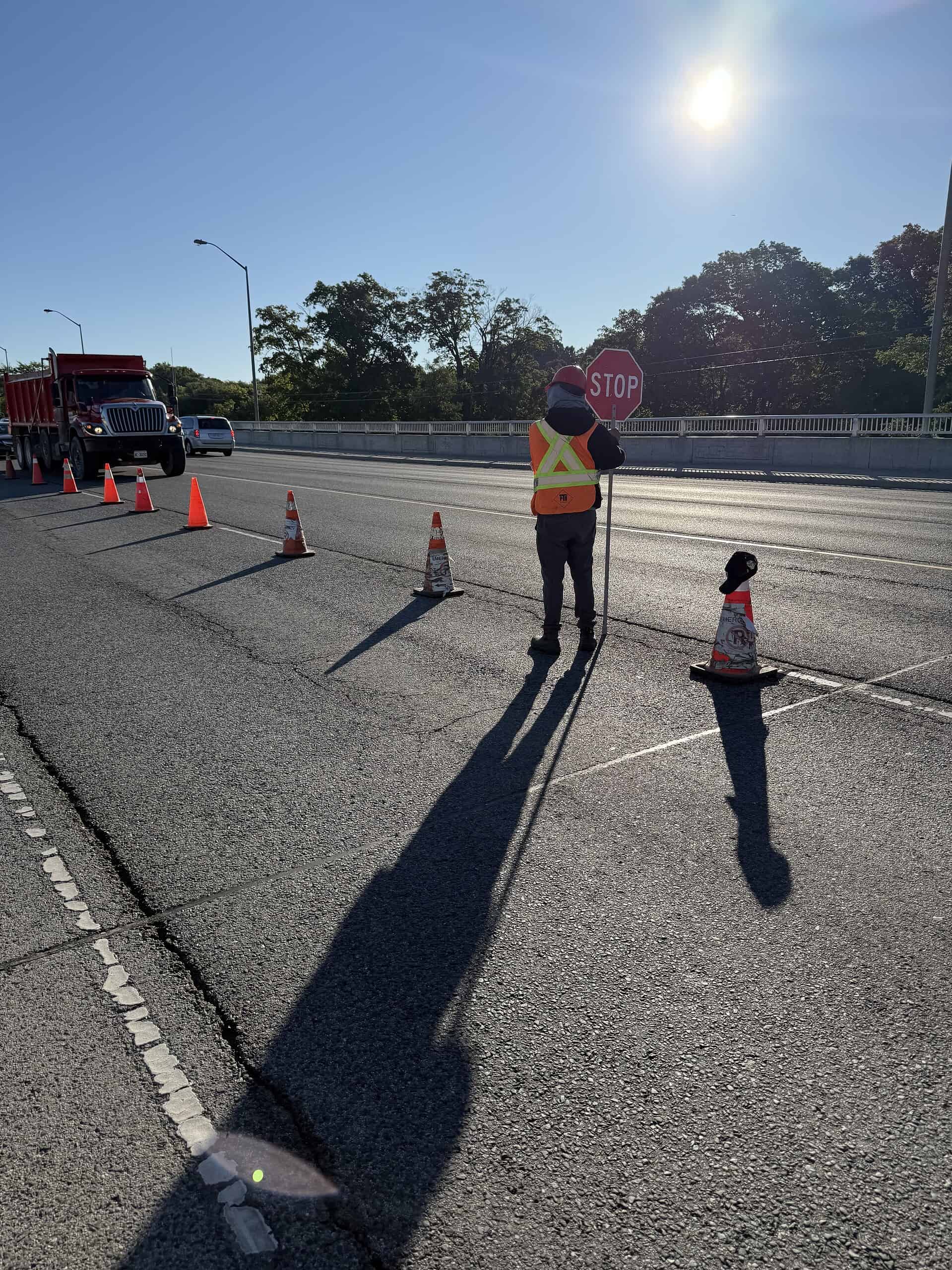 Construction worker holding stop sign on busy highway for roadwork safety.