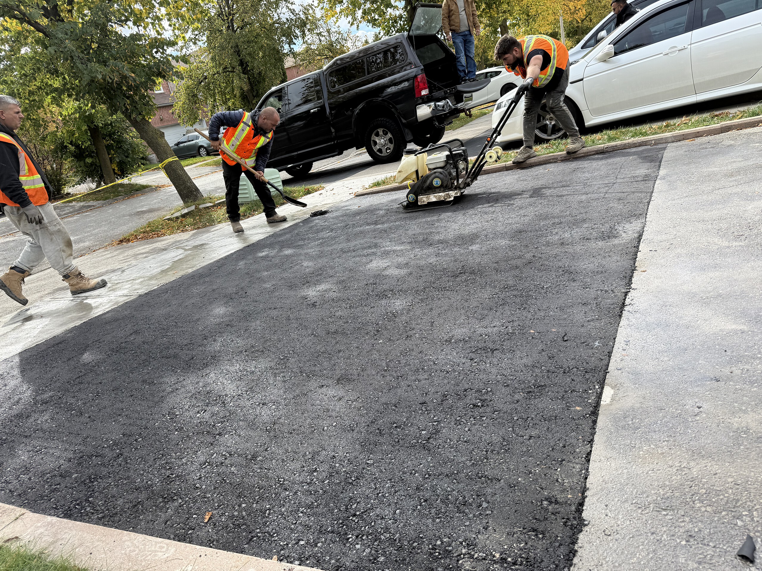 Paving crew working on asphalt driveway repair, showcasing professional asphalt paving and resurfaci.