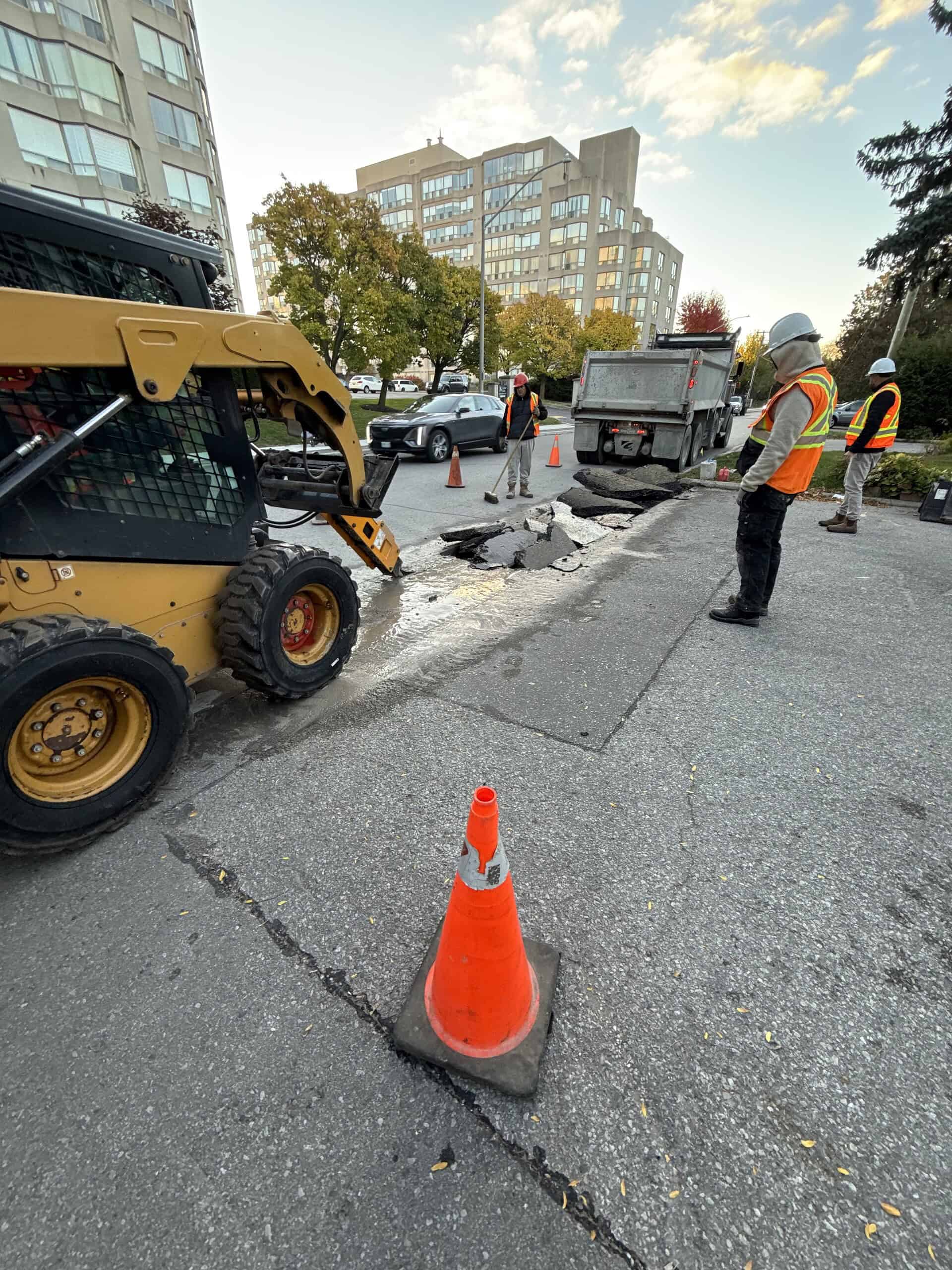 Road repair work with construction equipment and workers in urban area.