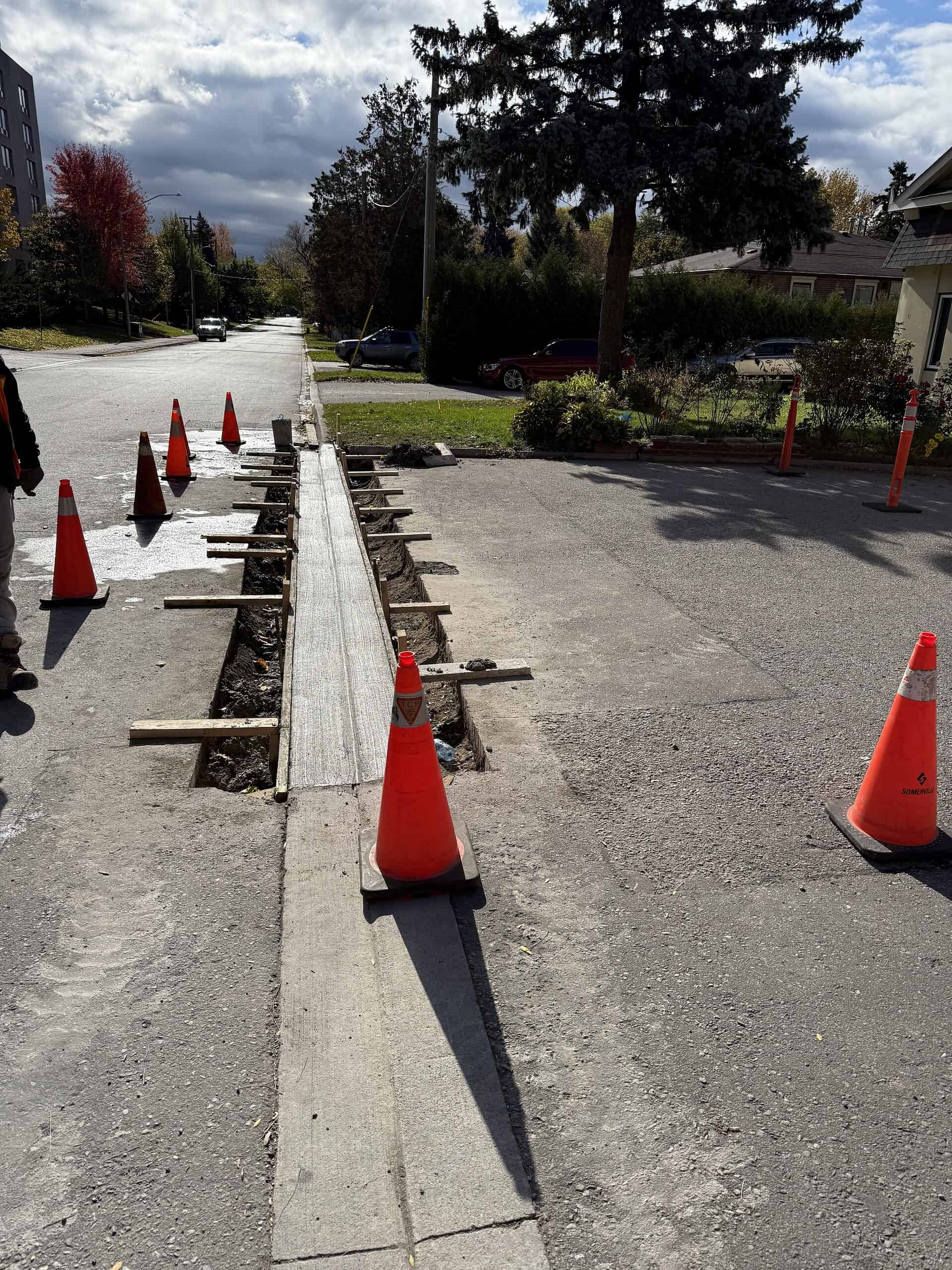 Road construction with safety cones and barriers in a residential neighborhood.