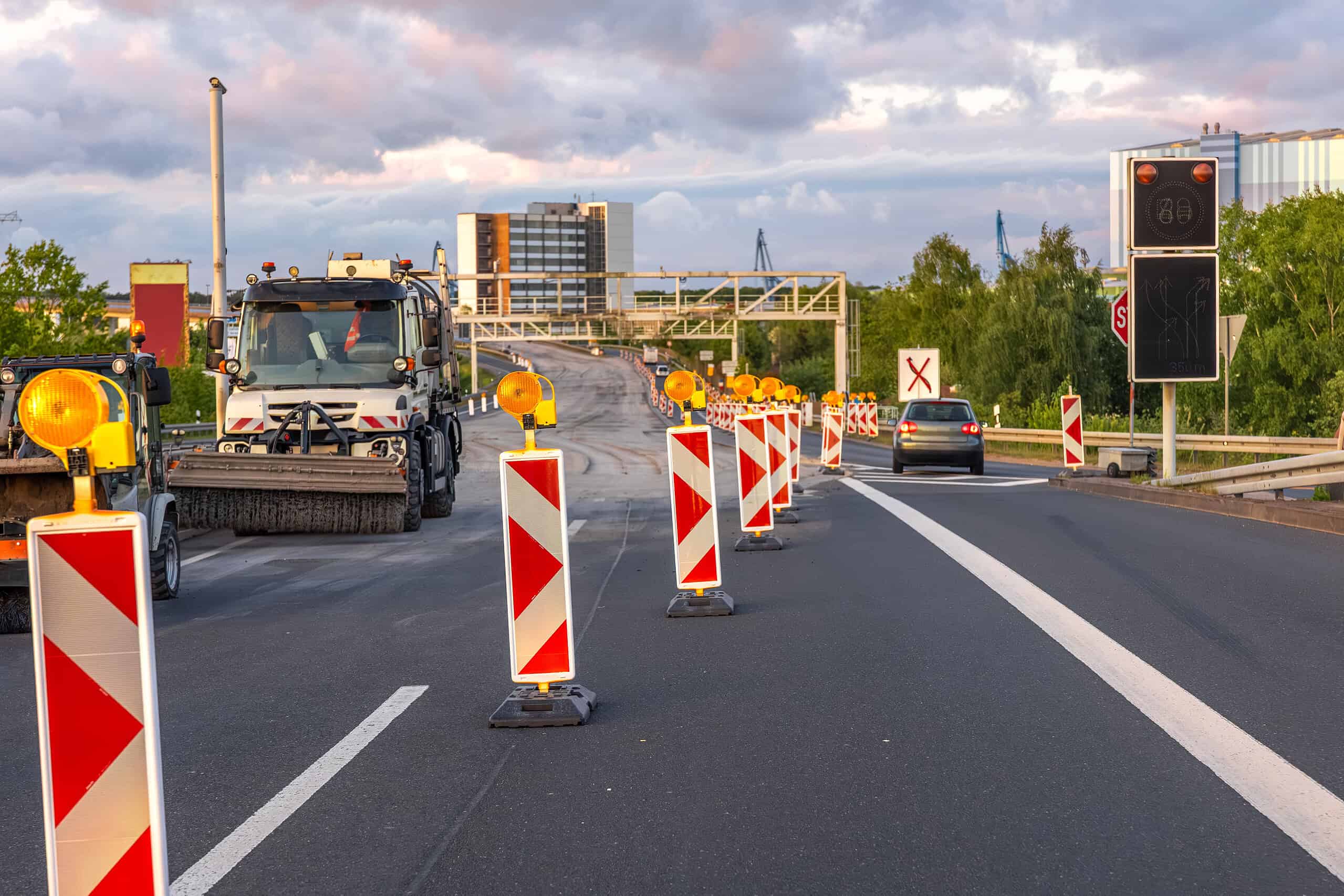 Road construction barriers and maintenance vehicles on a highway.