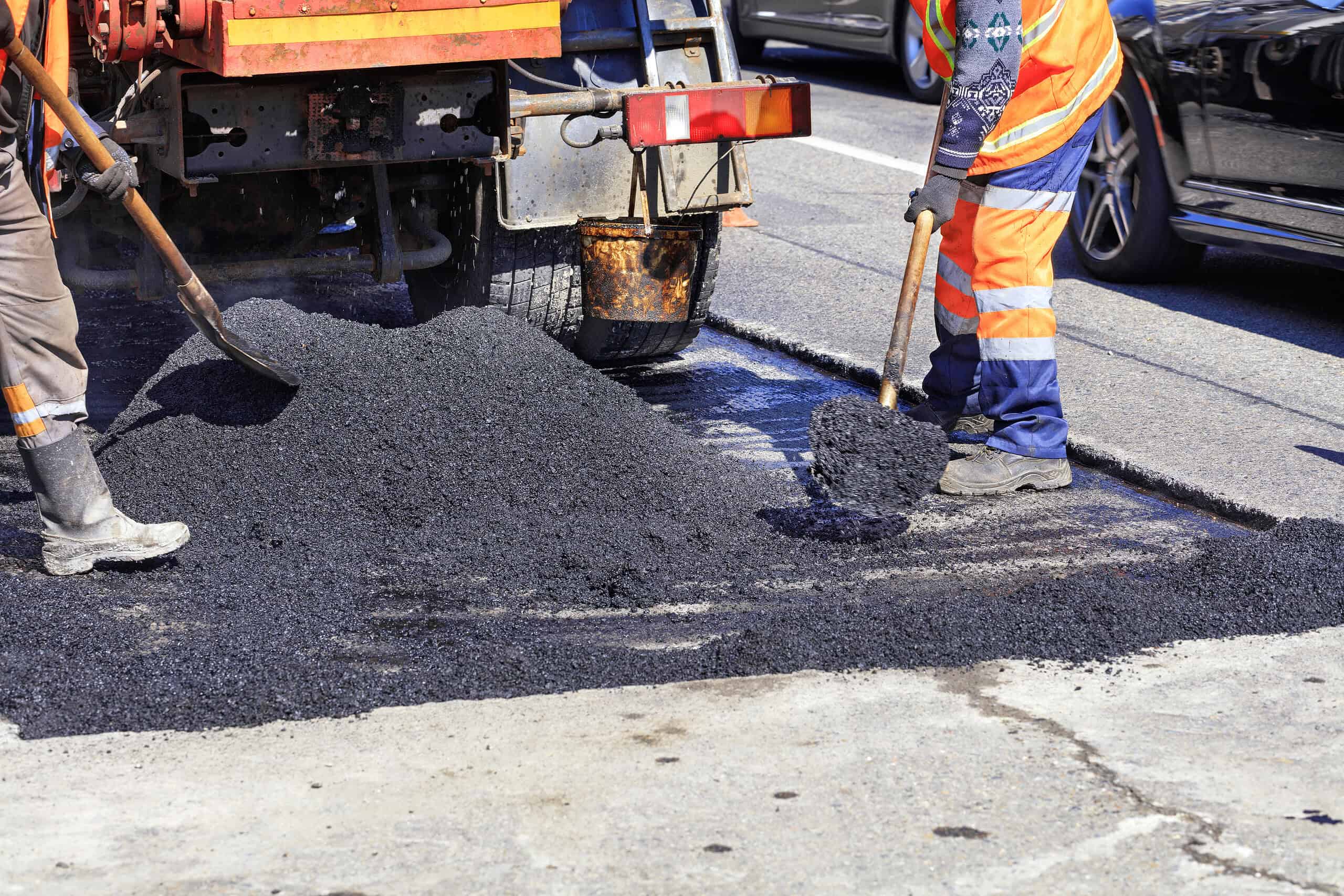 Paving crew laying asphalt on a road for construction project.